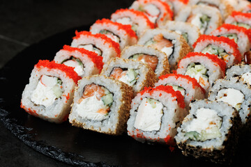 Assorted sushi rolls with fresh ingredients on a dark background. Ideal for restaurant, menu or Japanese food design.