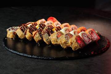 Assorted sushi rolls with fresh ingredients on a dark background. Ideal for restaurant, menu or Japanese food design.
