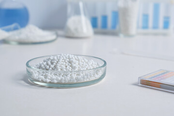 Laboratory Petri dishs with white granules on a background of chemical tools and glassware.