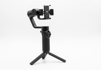 Handheld three axis gimbal stabilizer for a smartphone mounted on a mini tripod isolated on a white background for smooth filming