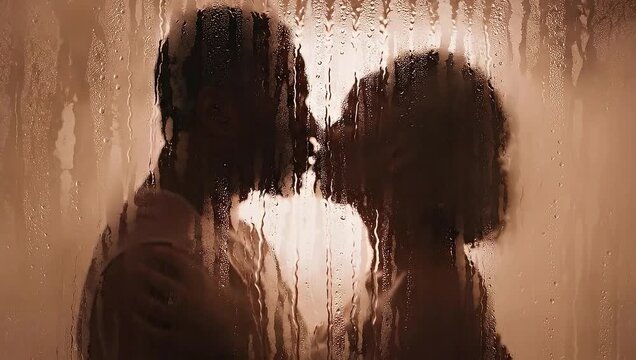 Sensual Moments: An intimate, silhouette portrait of a couple sharing a tender embrace in a moment of passion behind the misty glass. A timeless representation of romance.