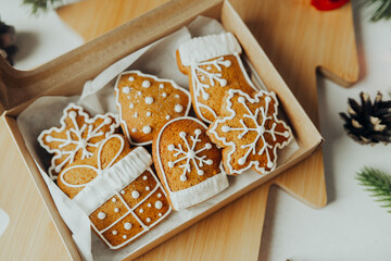 Box of festive gingerbread cookies decorated with white icing in holiday shapes
