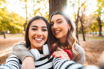 Obraz premium Joyful autumn moments shared by two friends in a sunlit park