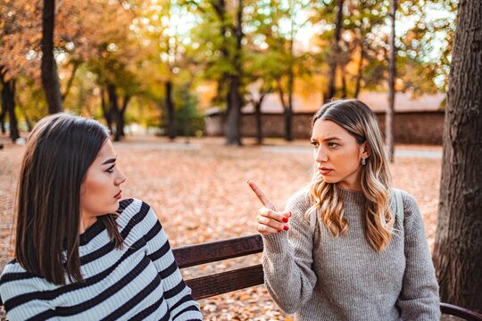 Two girls share a heartfelt conversation in a colorful autumn park