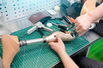 Prosthetist works on a prosthetic limb in a workshop, using tools and materials to create a custom replacement for a person with a disability