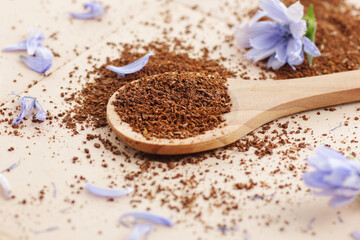 Ground chicory root powder in a wooden spoon, healthy coffee substitude drink, closeup, natural medicine and naturopathy concept