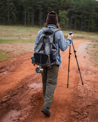 Woman hiking mountain trail with backpack, trekking pole
