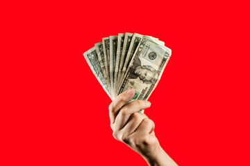 Hand holding US dollar bills on red background. Man holding cash money, concept of finance,...