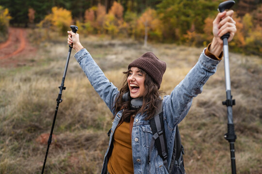 Happy woman celebrating achieving trekking goal in autumn forest