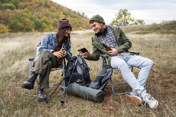 Fototapeta premium Young couple relaxing outdoors looking at smart phone