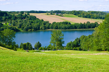 Idyllic lakeside landscape with rolling hills and summer sky, Kaszuby, Poland