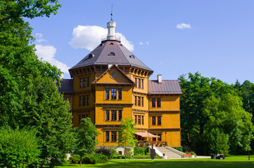 Historic yellow mansion surrounded by lush green trees, Antonin, Poland
