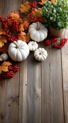 Colorful pumpkins and red berries are arranged with white flowers and autumn leaves on a rustic wooden surface