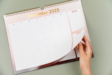 Woman hand is turning calendar page. December 2025 calendar page is open, transitioning into New year 2026
