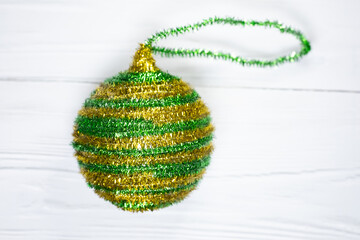 Green and gold Christmas tree ball on a light background. Christmas tree decoration. New Year and Christmas decorations.