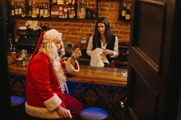 Fototapeta premium Tired santa claus having drink at bar