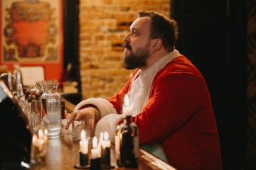 Tired santa sitting at bar enjoying drink