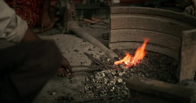 Cinematic shot of Indian blacksmiths forging tools like hoe, sickle, and  spade in a workshop
