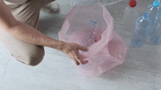 Man removing caps from plastic bottles to separate plastic types before recycling at home and put it into garbage bag. Recycling, waste separation, and sustainable living. Eco habits at home. Top view