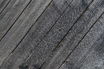 Close-up of old, grey, weathered wooden planks arranged diagonally as a back
