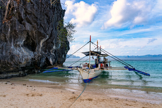 Boot neben einer Felswand am Strand von Seven Commandos Beach, Palawan, auf den Philippinen