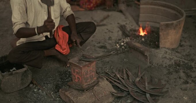 Cinematic shot of Indian blacksmiths forging tools like hoe, sickle, and  spade in a workshop