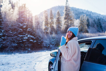 Happy woman admiring snowy mountains walking out of car looking at winter landscape. Traveling by auto. Space