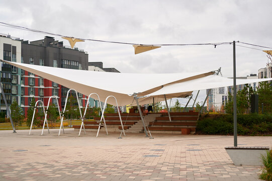 modern urban park with architectural shade structure showcasing innovative design amidst residential buildings. provides functional aesthetic appeal, inviting outdoor gathering space, contemporary