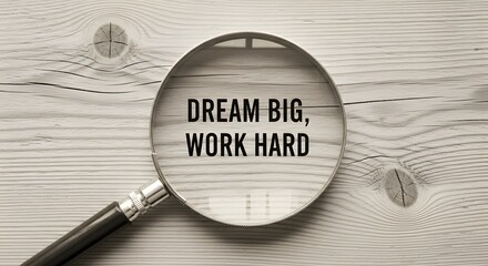 Dream big and work hard motivational concept, empowering words of wisdom, inspirational message with magnifying glass on rustic wooden surface, success mindset