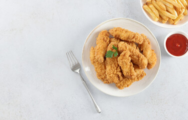 Crispy chicken strips with ketchup and French fries on a white background. Fast food. Copy space