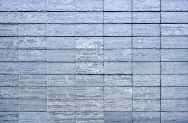 Blaugraue rechteckige Schieferplatten als Wandverkleidung an einer Fassade