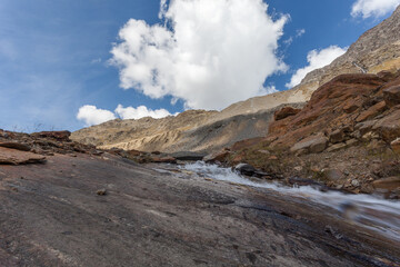 Mountain stream over rocks smoothed by the Vallelunga Glacier with moraines of 1850 age that indicate the enormous retreat of the glacier that occurred due to global warming, Alto Adige, Italy