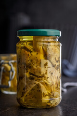 Pickled artichoke in jar on black table.