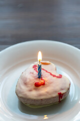 Close-Up of Heart-Shaped Strawberry Birthday Cake with a Burning Candle on a White Plate
