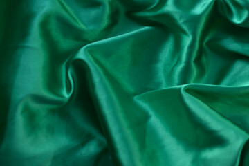  A closeup minimalist textured pattern. Green satin fabric texture luxurious shiny. Background with pattern soft waves blur beautiful.