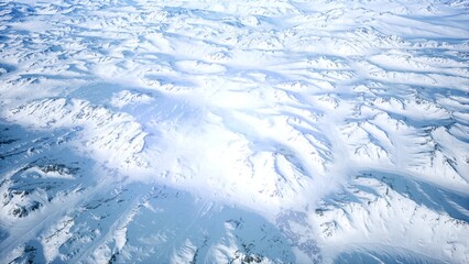 A breathtaking aerial view reveals a vast landscape of snow covered mountains bathed in soft morning light. Intricate patterns in the snow create a mesmerizing tapestry of winter tranquility.