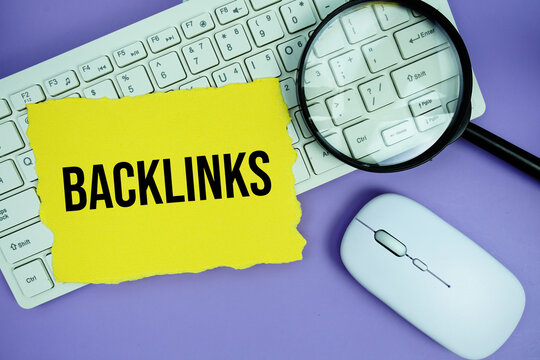 Yellow torn paper with the text "Backlinks" placed on a white keyboard, and magnifying glass and a computer mouse