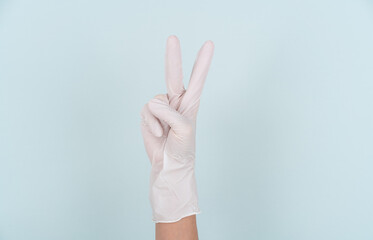 Making the number 2 gesture with a hand wearing a disposable glove