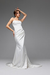 Fototapeta premium Elegant bride showcasing minimalist wedding gown in a natural light studio setting