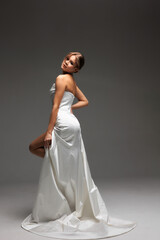 Naklejka premium Elegant bride showcasing modern bridal style in minimalist wedding gown with luxurious satin finish