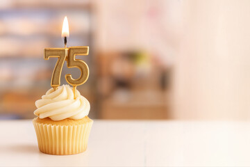Cupcake with number 75 candle burning brightly on top, set in a warm indoor environment, ideal for celebrating a milestone birthday or anniversary
