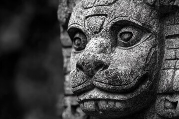 Close-up of an ancient, weathered stone carving depicting a mythical creature's face in stark black and white, showcasing intricate details and textures.