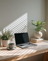 Fototapeta premium Minimalist home office workspace with laptop, potted plants, and coffee cup on a wooden desk bathed in natural light