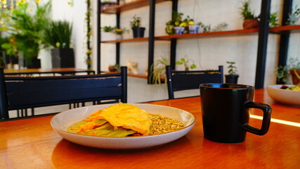 Platillo servido en plato artesanal con una omelette dorada acompañada de flor de calabaza y salsa verde.