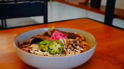 platillo de chilaquiles con carne de res encima y rodajas de chile verde con cebolla morada.