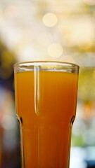 Vaso de jugo natural servido sobre una mesa de madera, con fondo cálido y detalles de vegetación.