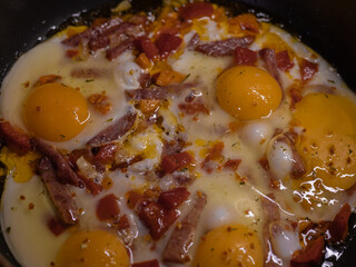 Scrambled eggs with vegetables and sausage in pan close-up