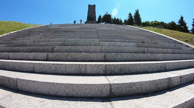 Low-angle handheld video of walking up the stone stairs leading to the Shipka Monument with the tower visible in the distance, Bulgaria, 20 May 2021