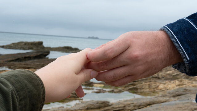a couple holding hands at the beach - Powered by Adobe