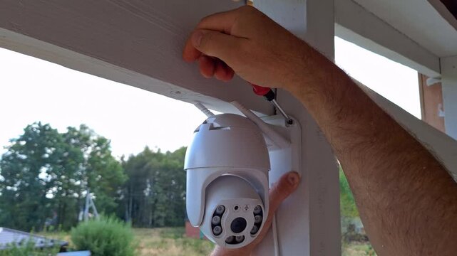 Installing modern outdoor security camera under eaves with handson assembly process